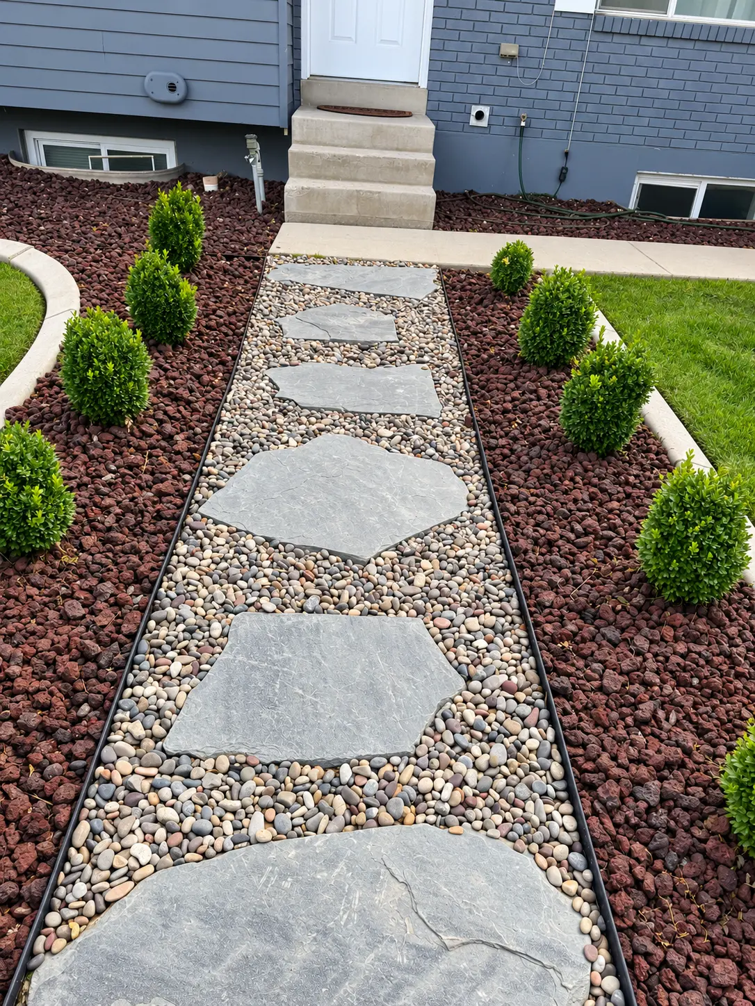 Black barn with paver walkway, raised planters, ornamental grasses, and lawn